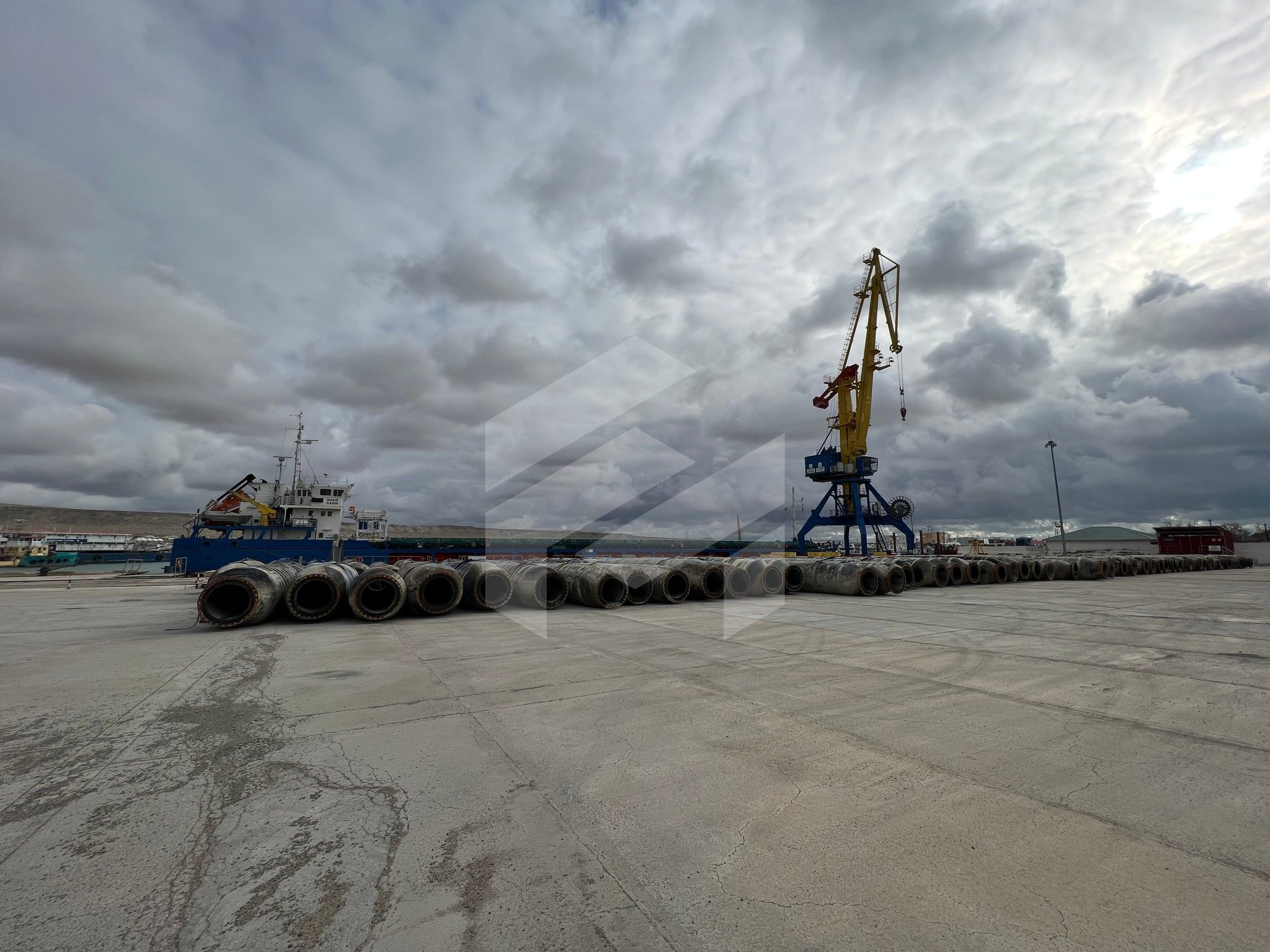 Floating pipes lined up on the quay under a cloudy sky