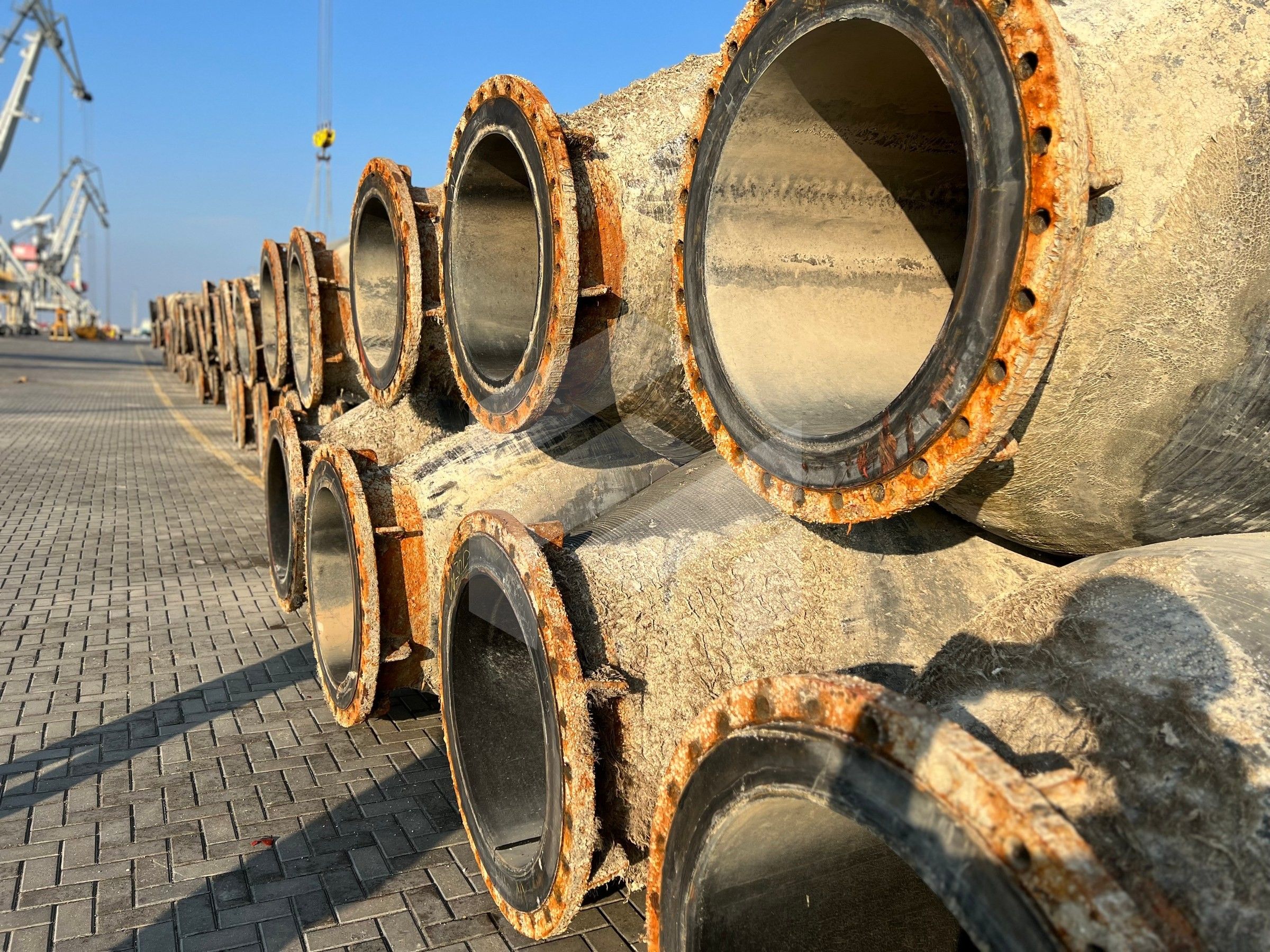 Stacked floating pipes with flanged ends on the quay